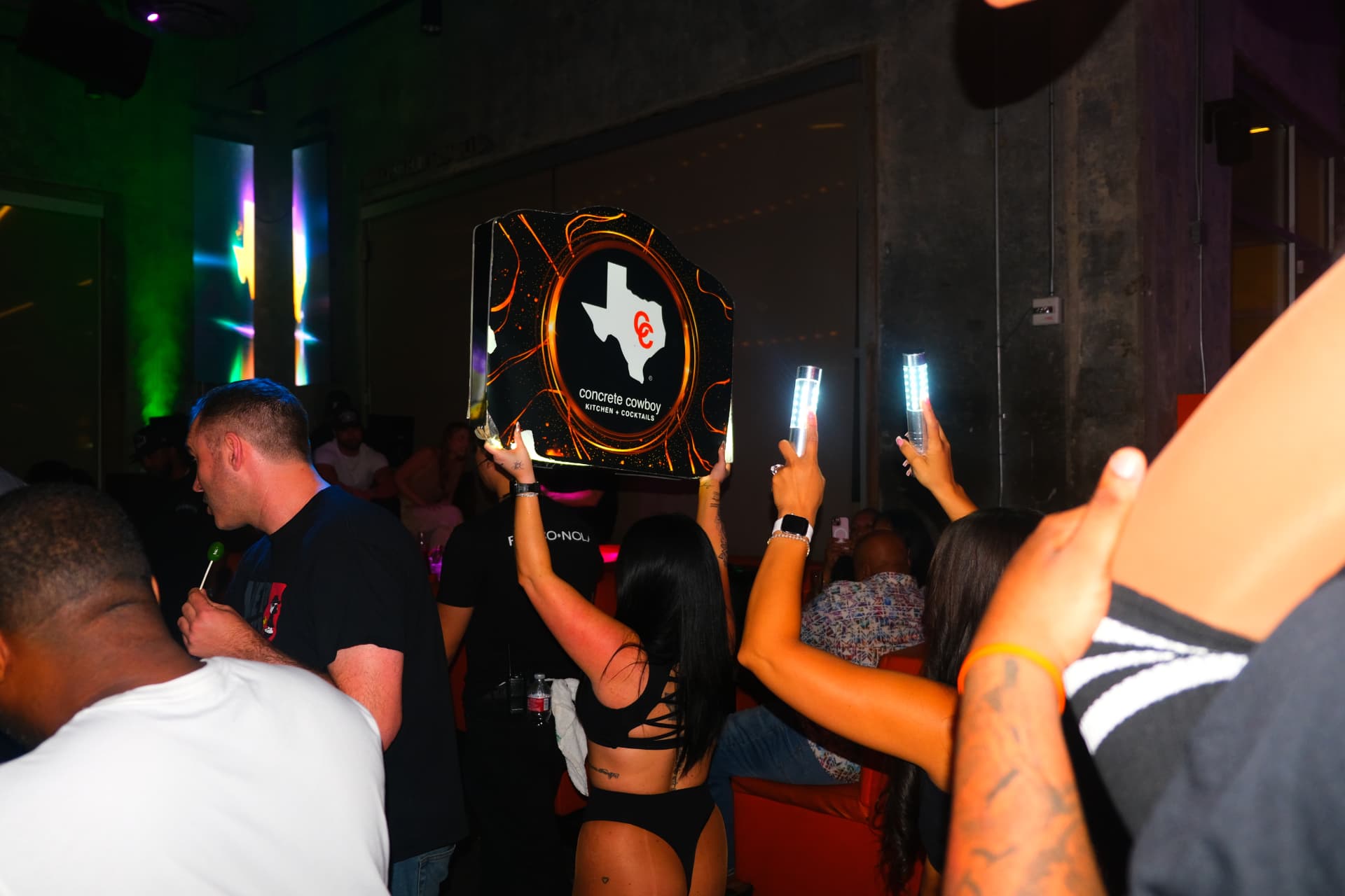 Glowing Texas-shaped Concrete Cowboy table service sign held above the crowd