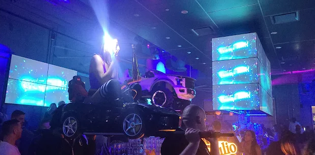 Packed nightclub floor lit by blue laser beams and LED towers
