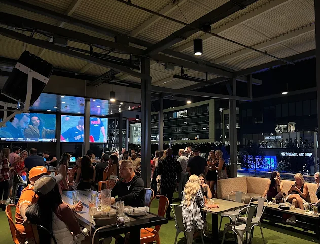 Night rooftop crowd under string lights with the Frisco skyline behind