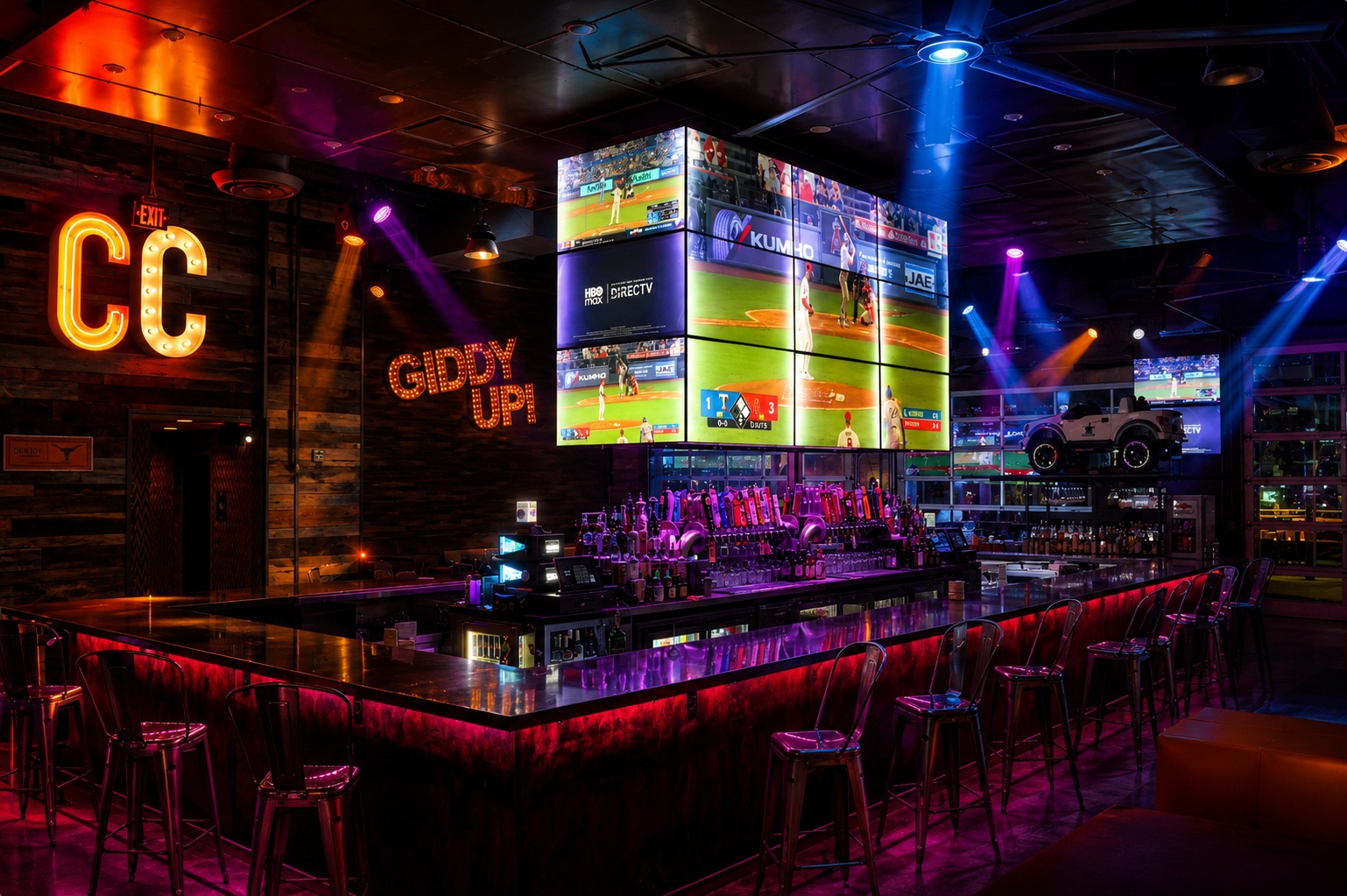 Concrete Cowboy Frisco bar interior with the illuminated CC and GIDDY UP! signs and a massive video wall above the bar